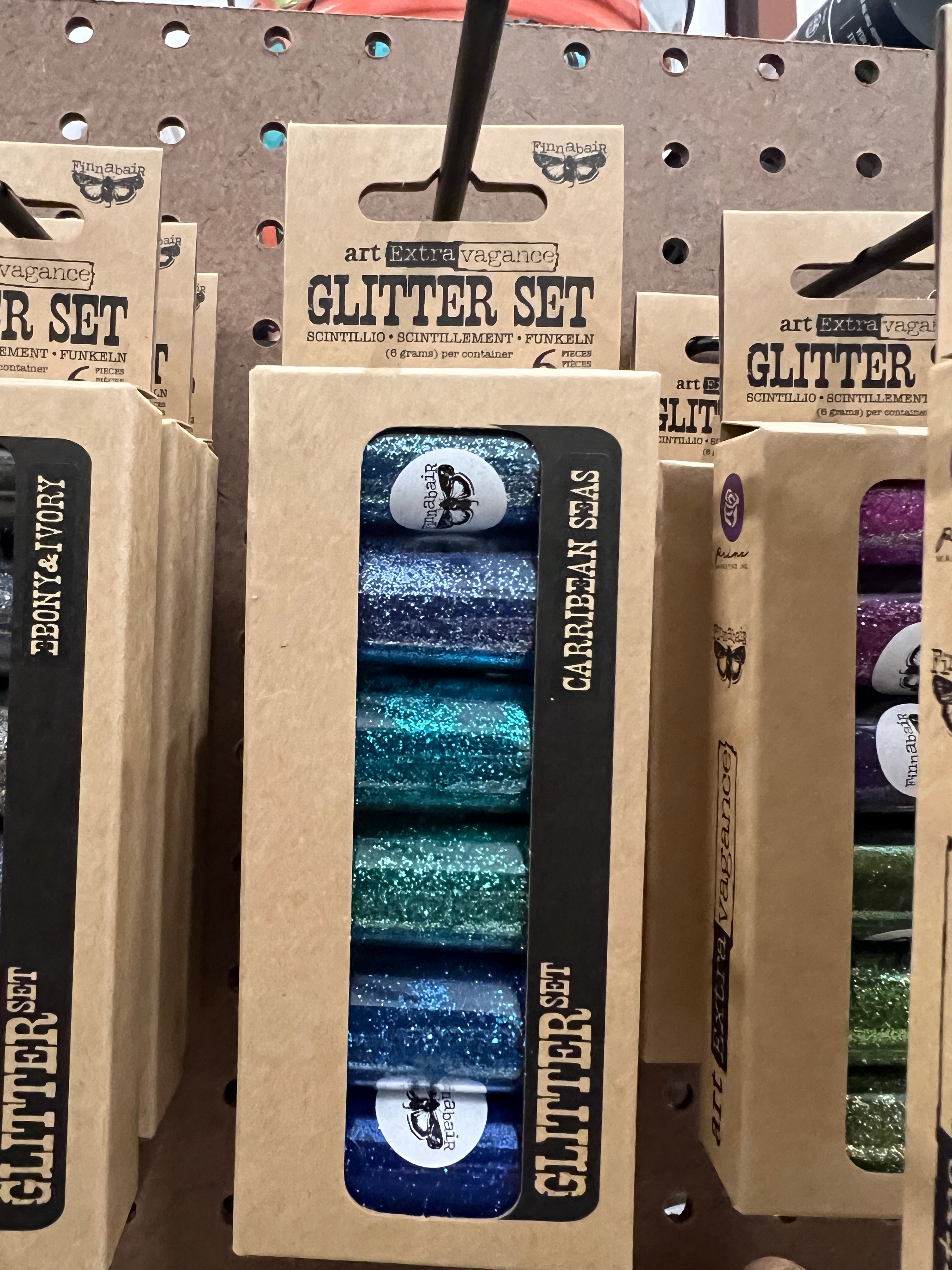 Box of glitter set with visible brand name on a pegboard background