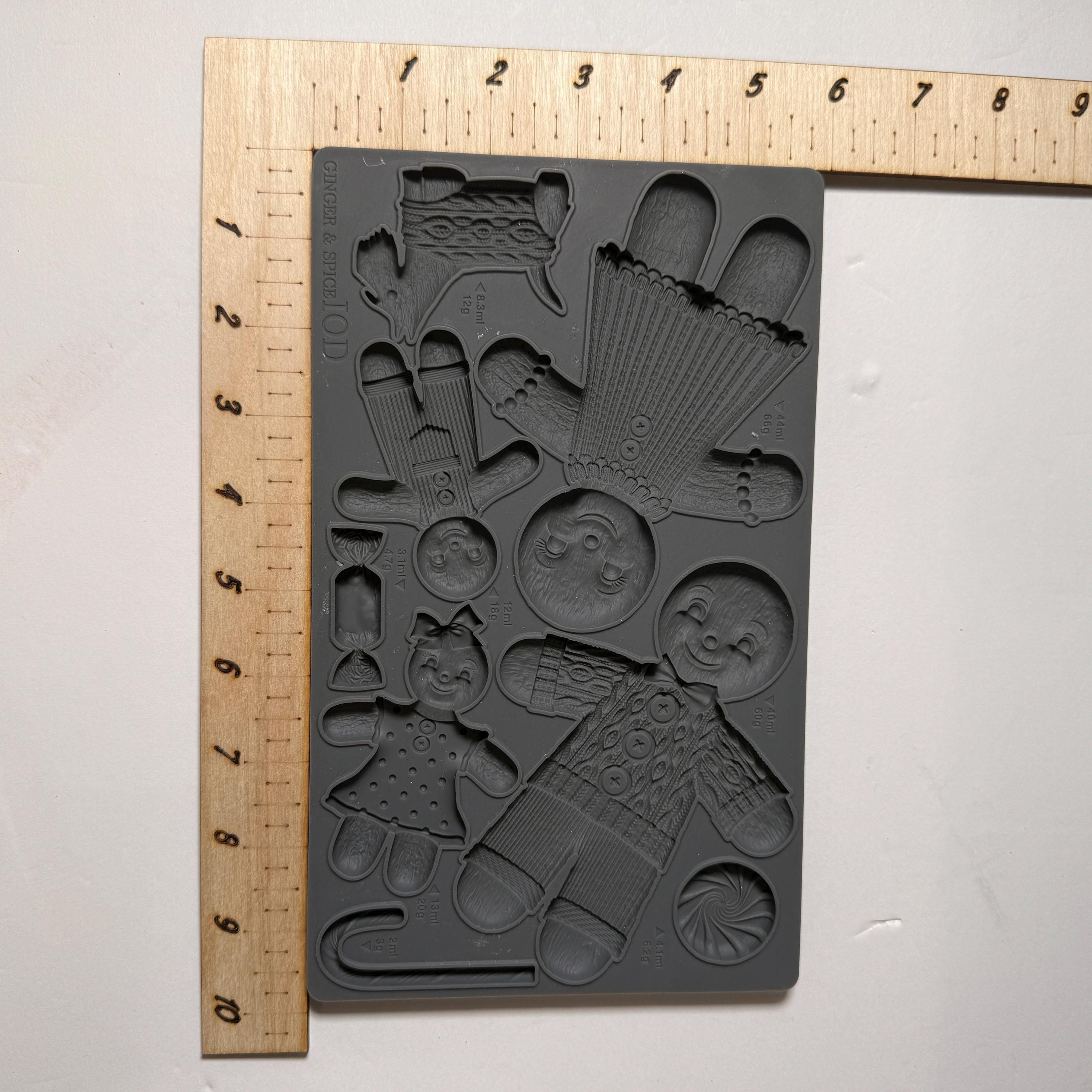 Black silicone mold with various shapes next to a ruler on a white background