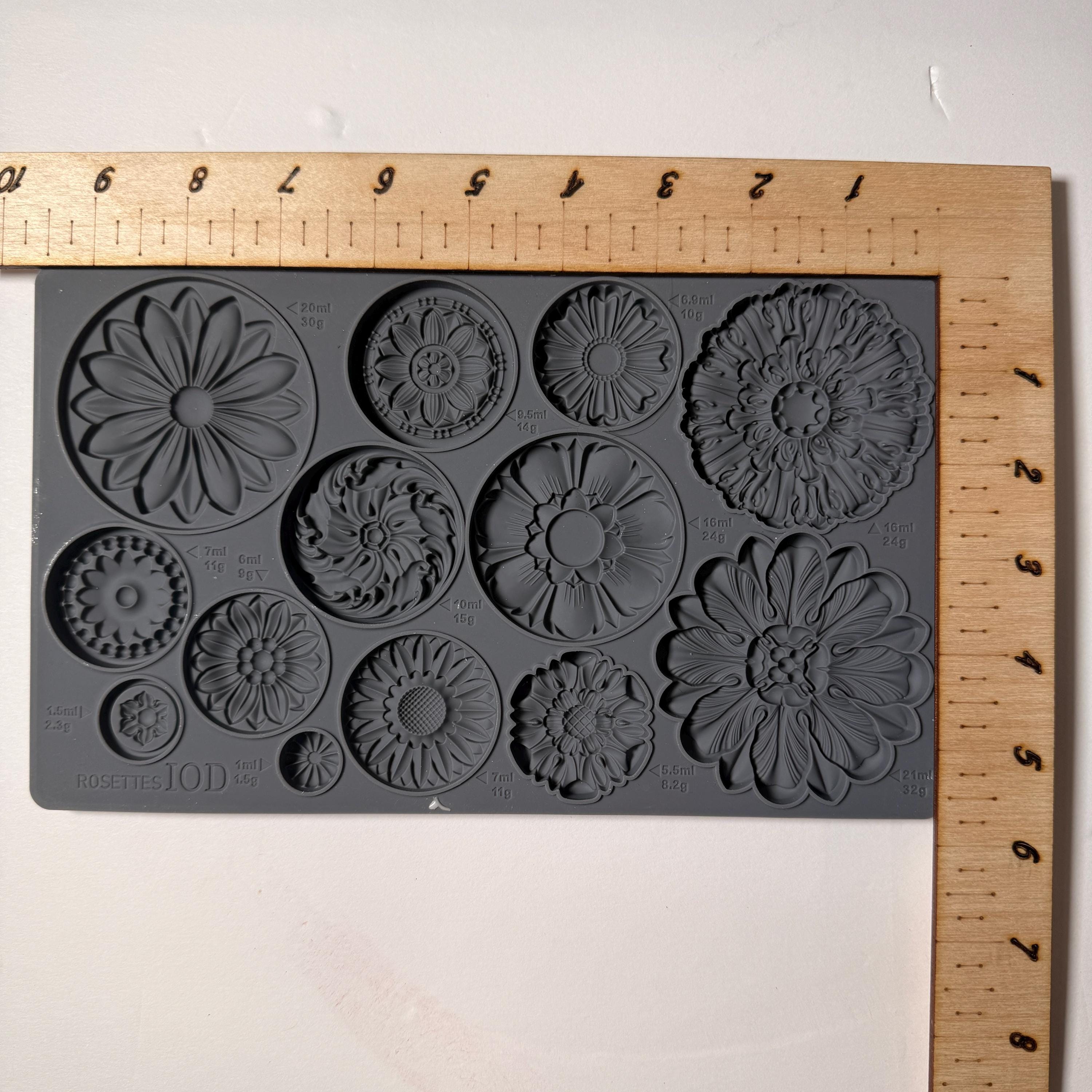 Floral silicone mold on a gray background with a wooden ruler for scale.