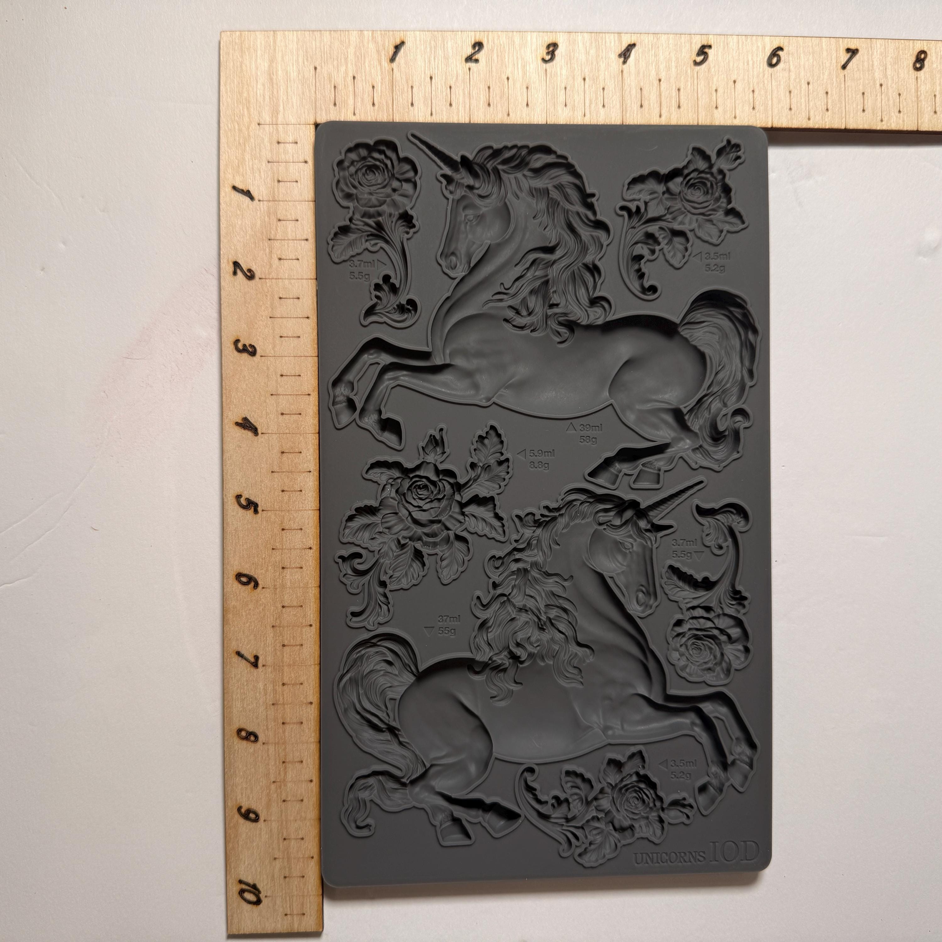 Silicone mold with unicorn design on a gray background, measured against a ruler.