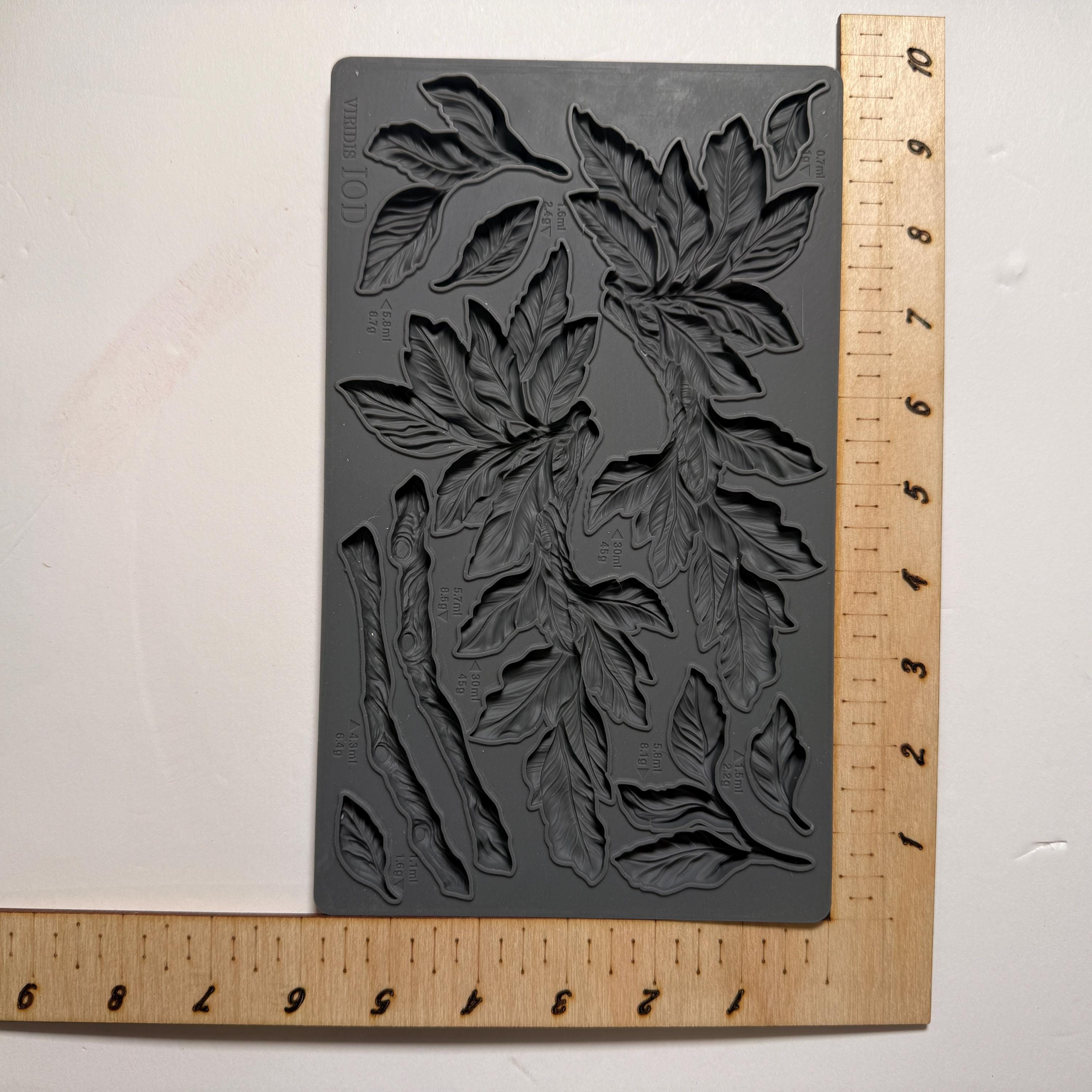 Decorative leaf mold on a white background with a ruler for scale.