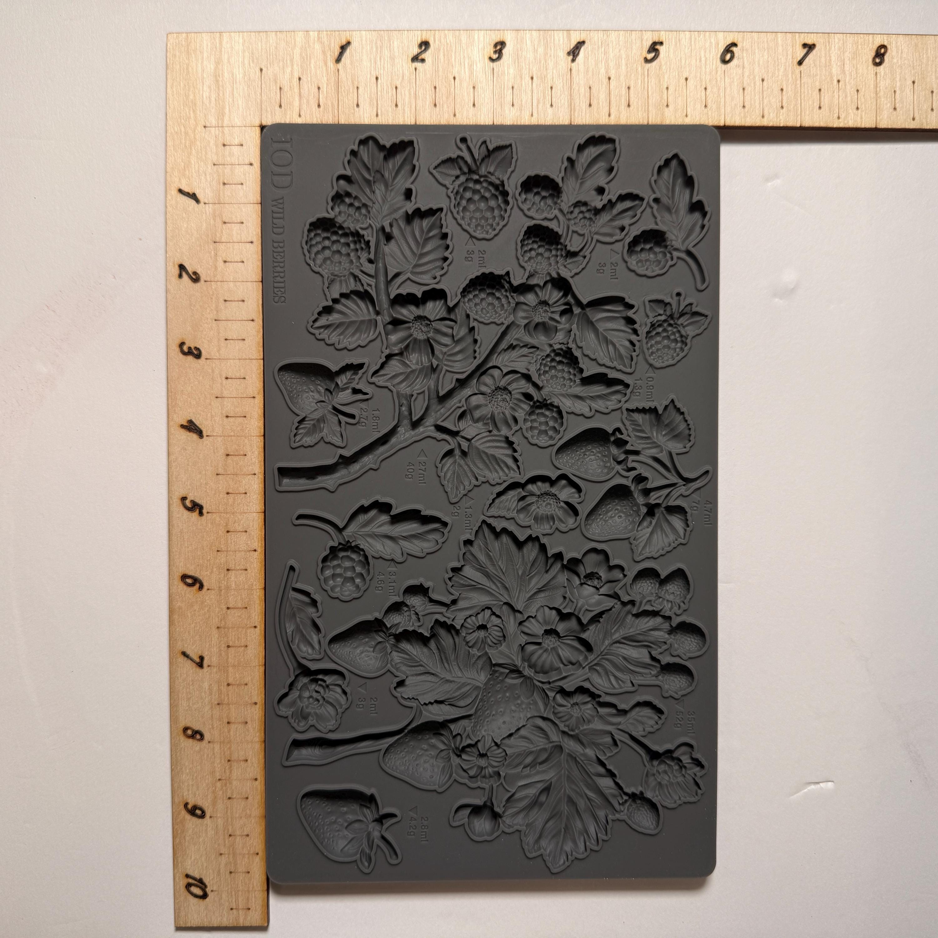 Decorative mold with floral design next to a ruler on a light background