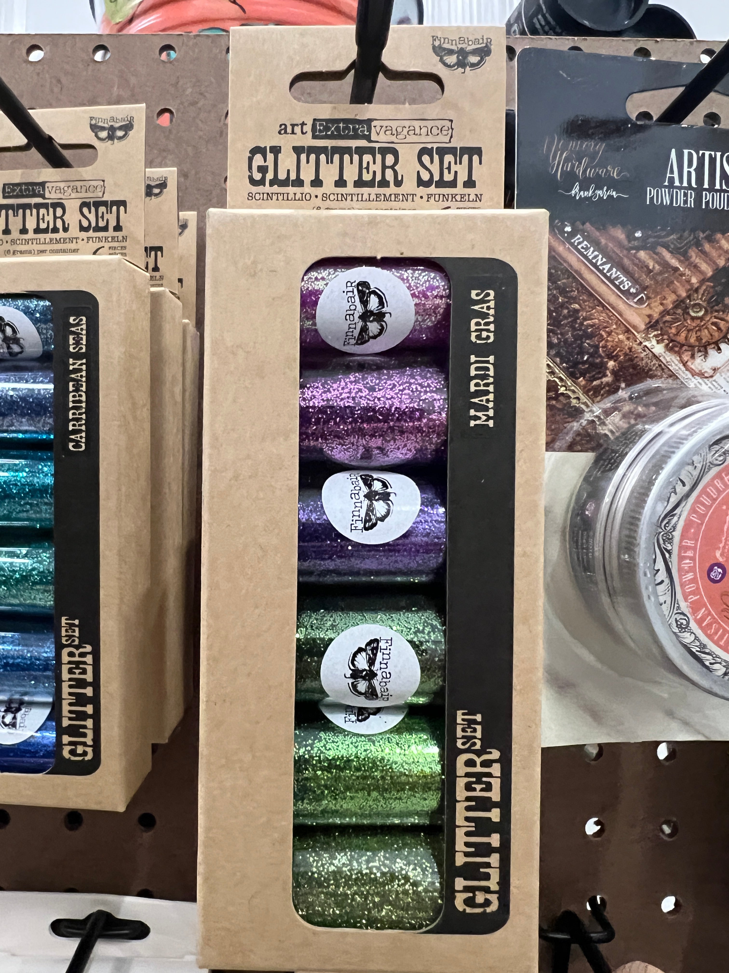 Packaged glitter sets with visible brand names on a display stand.