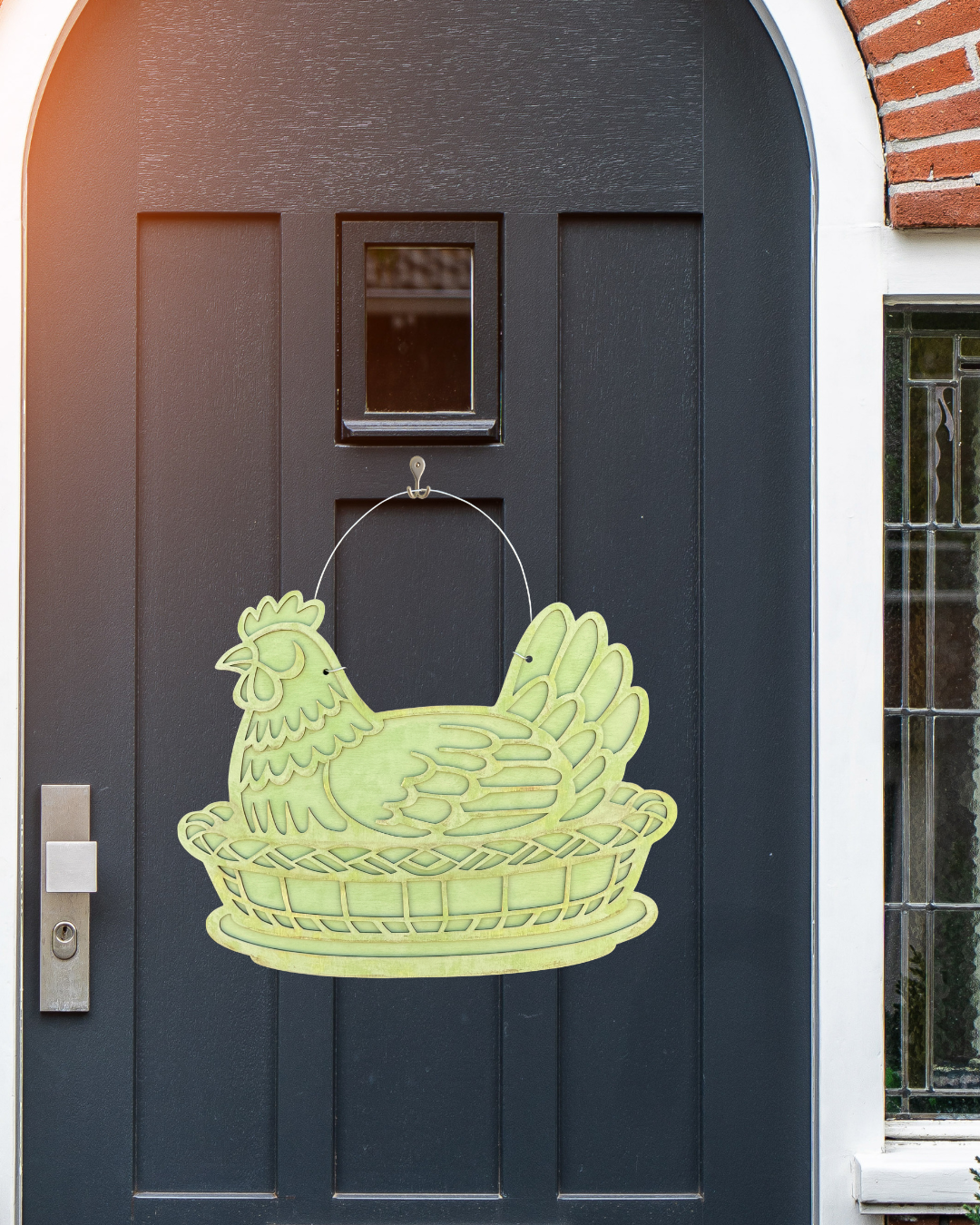 Decorative chicken-shaped door hanger on a dark gray door.