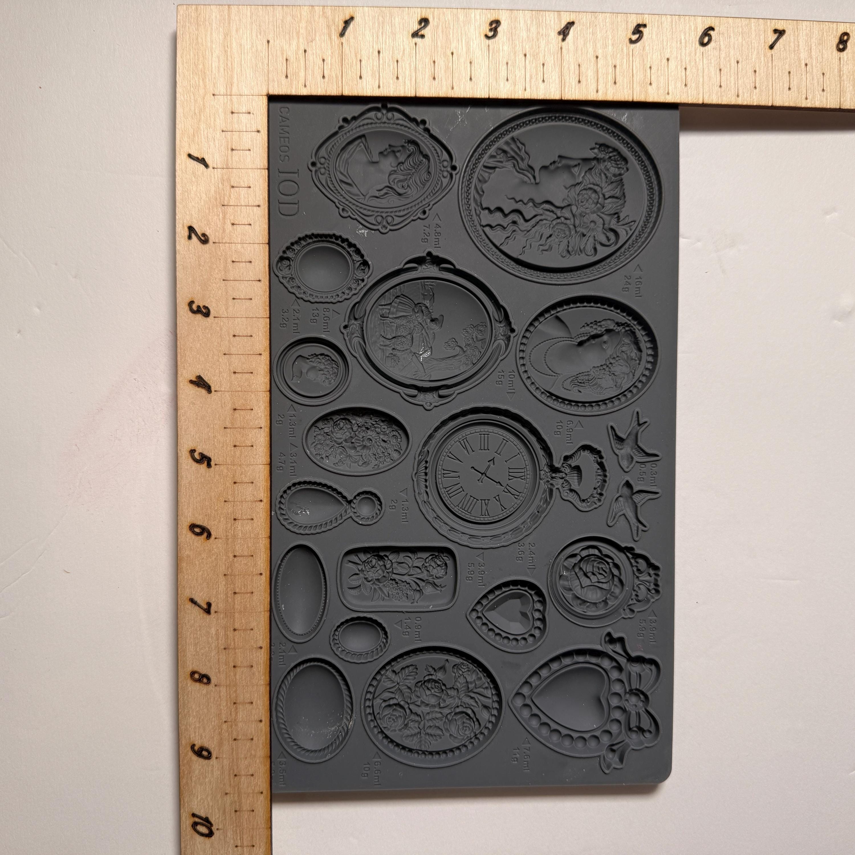 Silicone mold with various shapes next to a ruler on a beige background