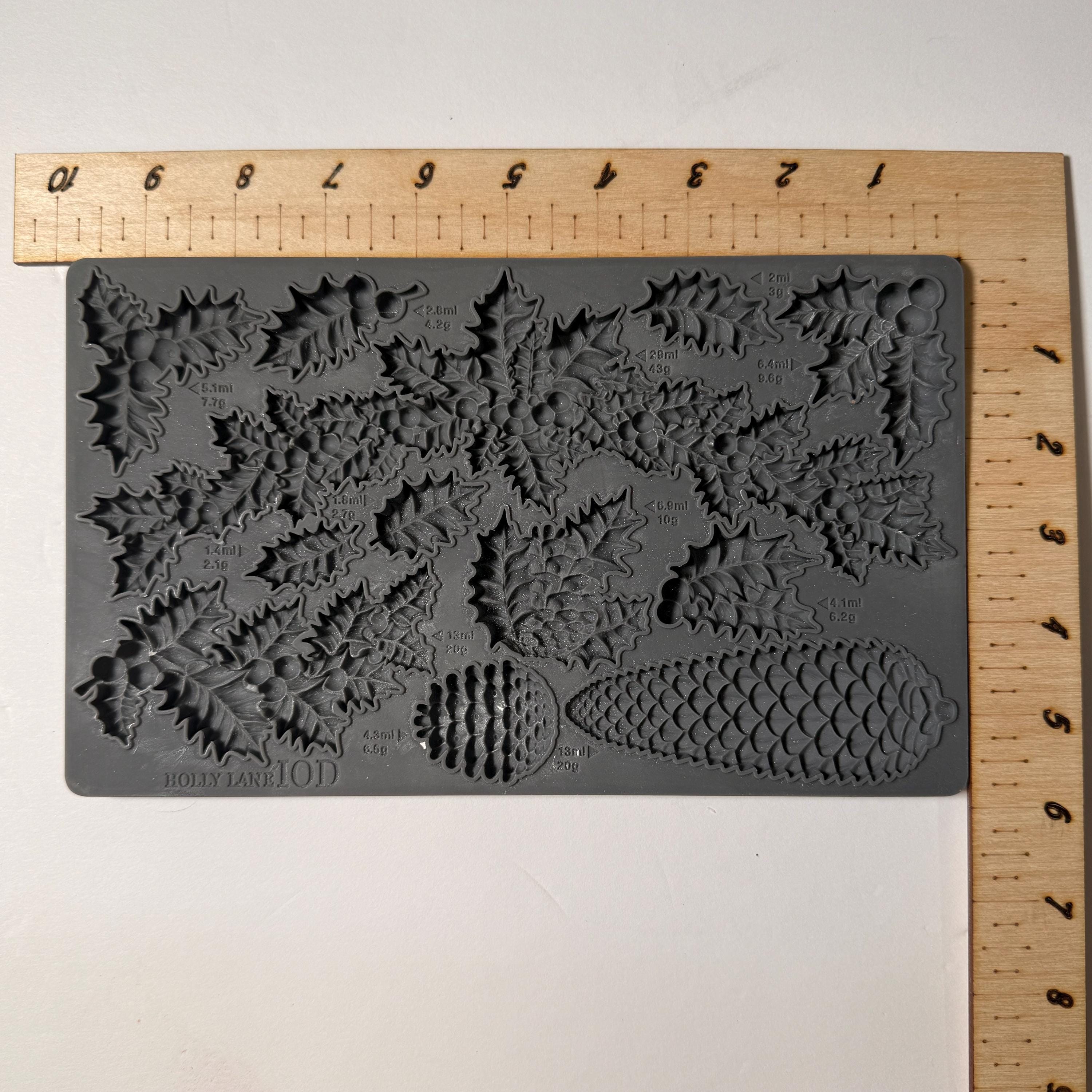 Gray mold release sheet with pine cone and leaf patterns on a wooden ruler.