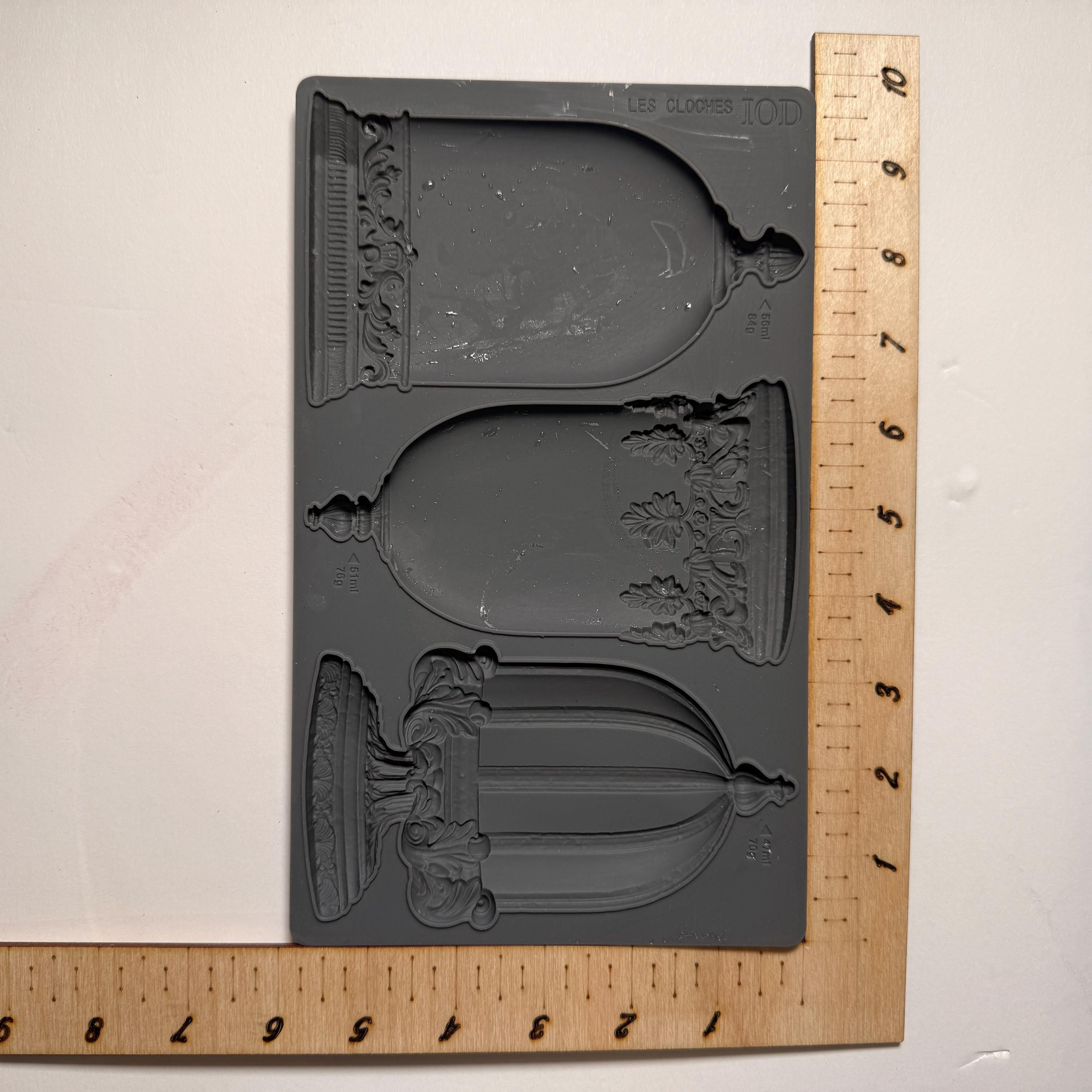 Decorative silicone mold with intricate designs on a wooden ruler for scale.