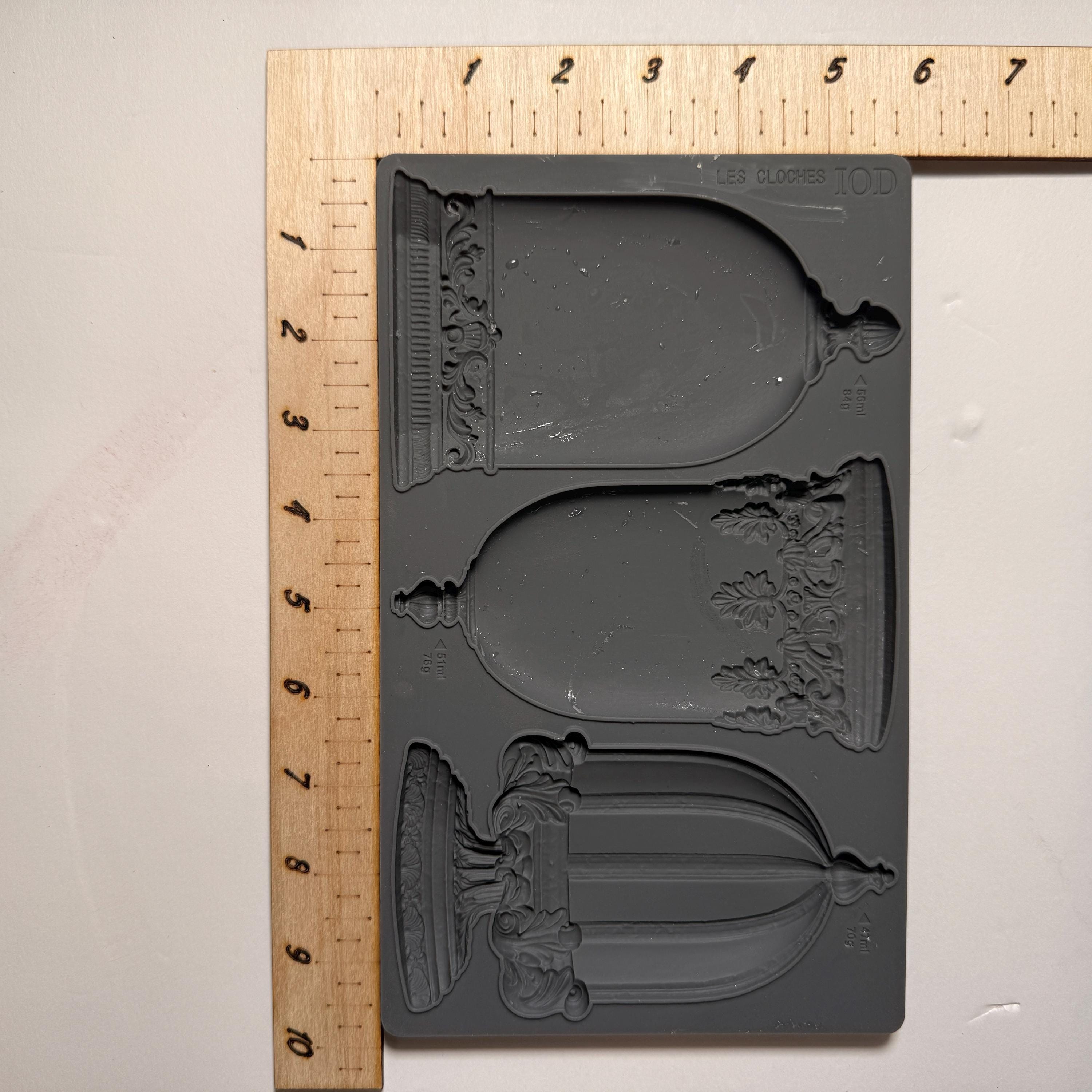 Silicone mold with decorative shapes on a wooden ruler for scale