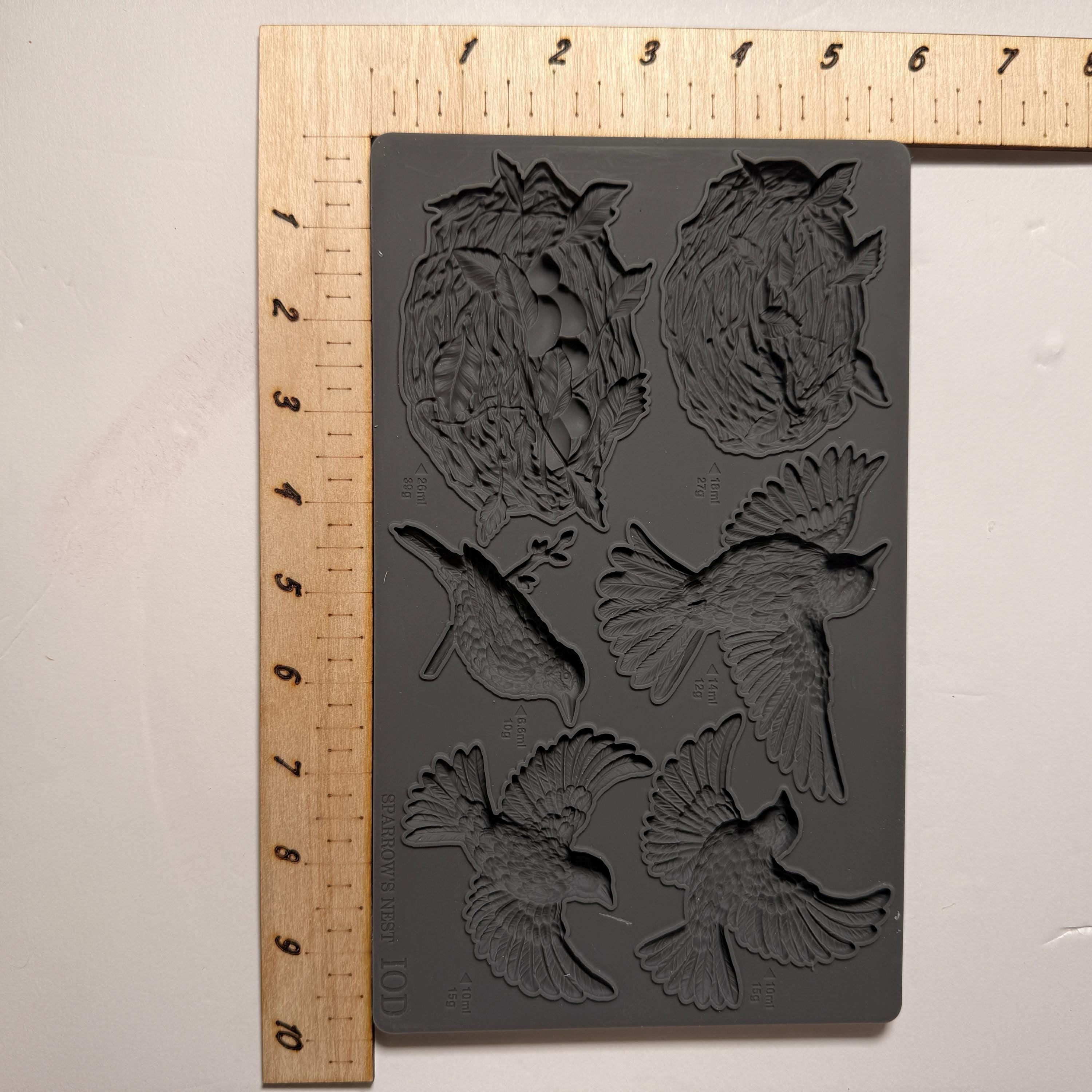 Silicone mold with bird designs on a wooden ruler for scale