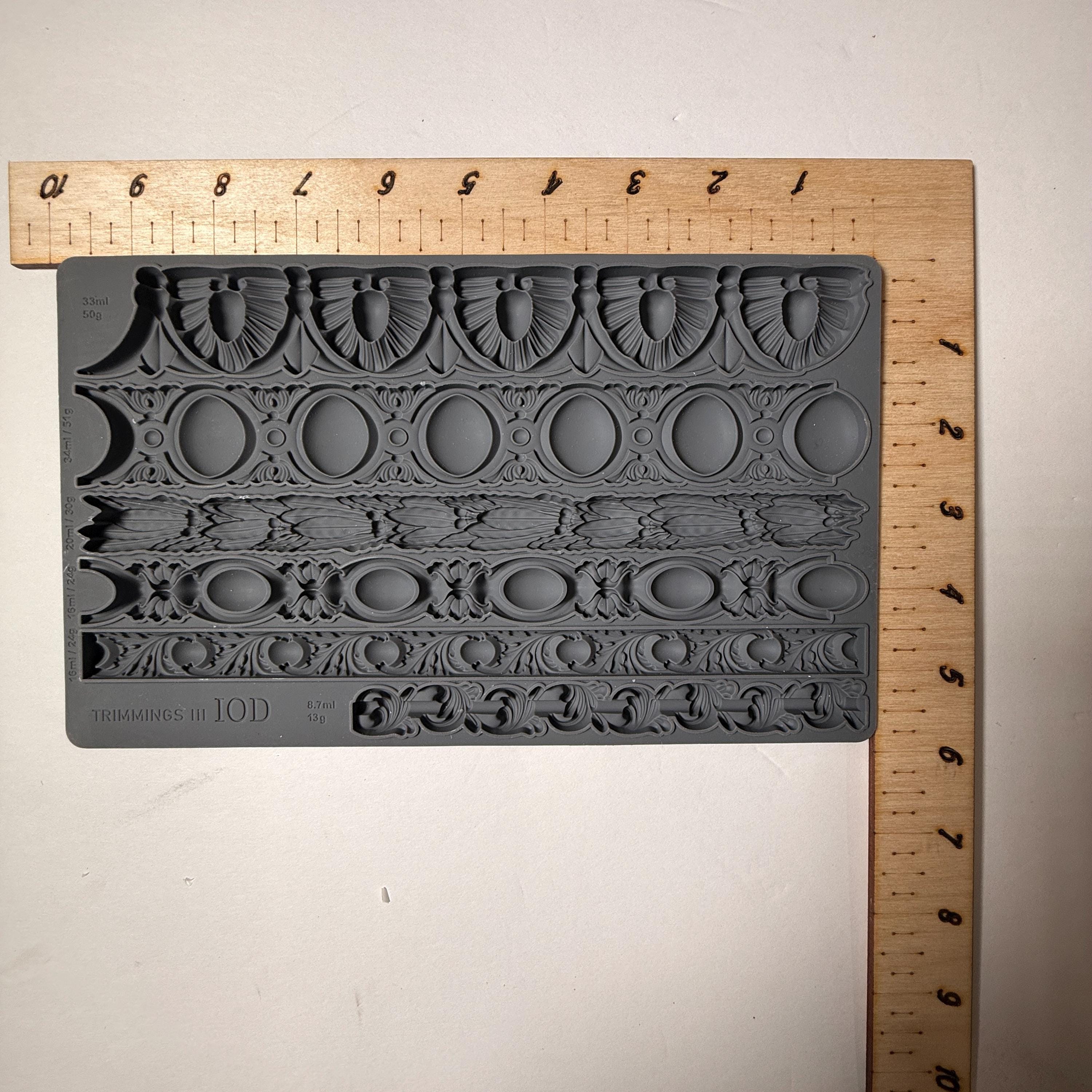 Decorative silicone mold with intricate design on a wooden ruler for scale.