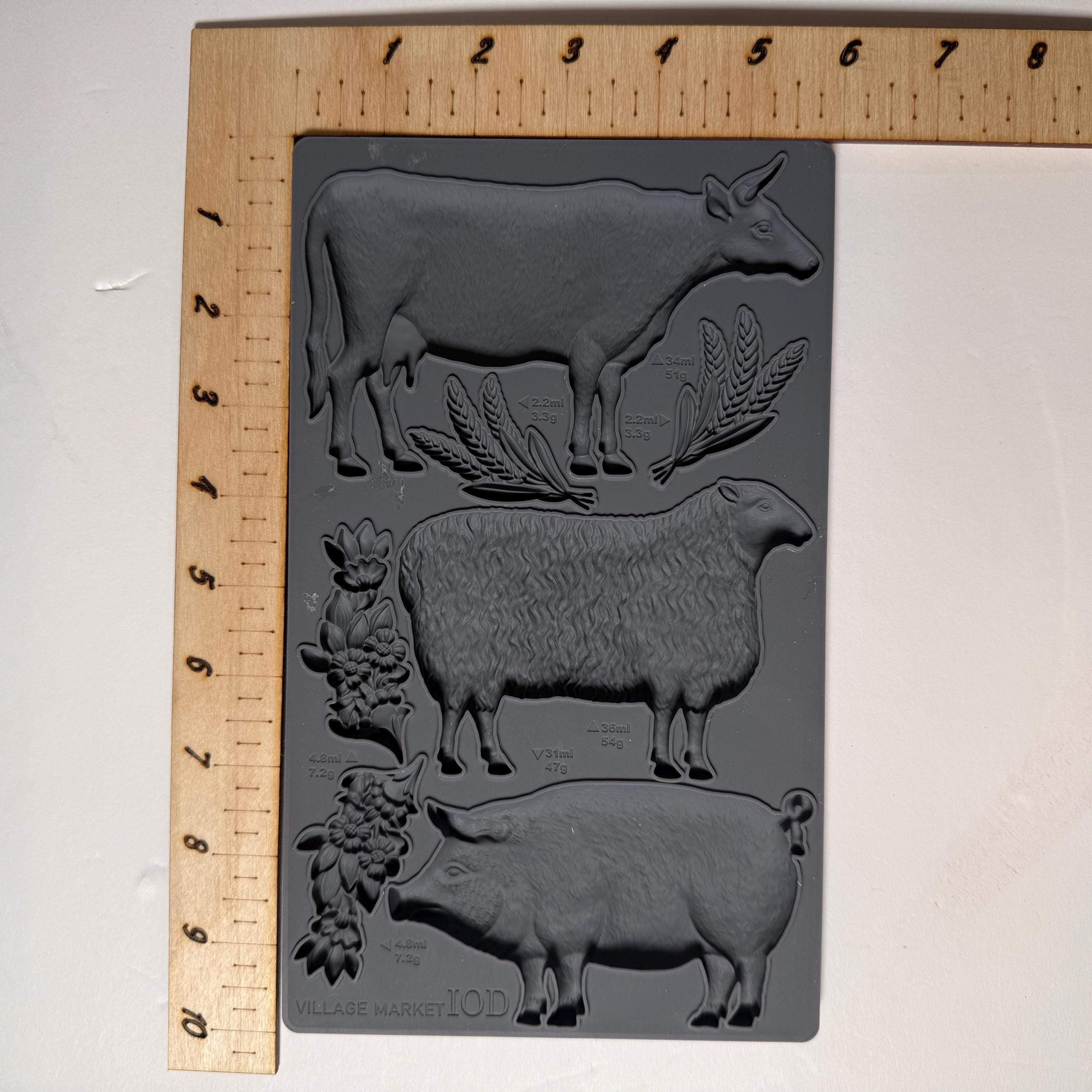 Silicone mold with cow, sheep, and pig shapes on a white background with a ruler for scale.